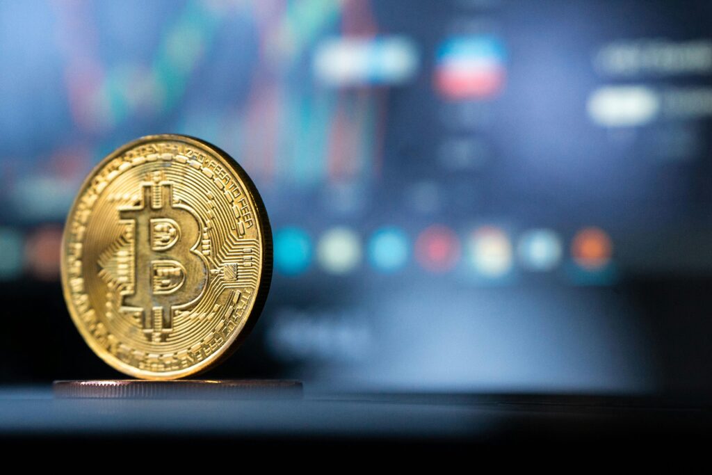pexels-photo-11070638-11070638 Gold Bitcoin coin with blurred financial chart in background, representing cryptocurrency trading.