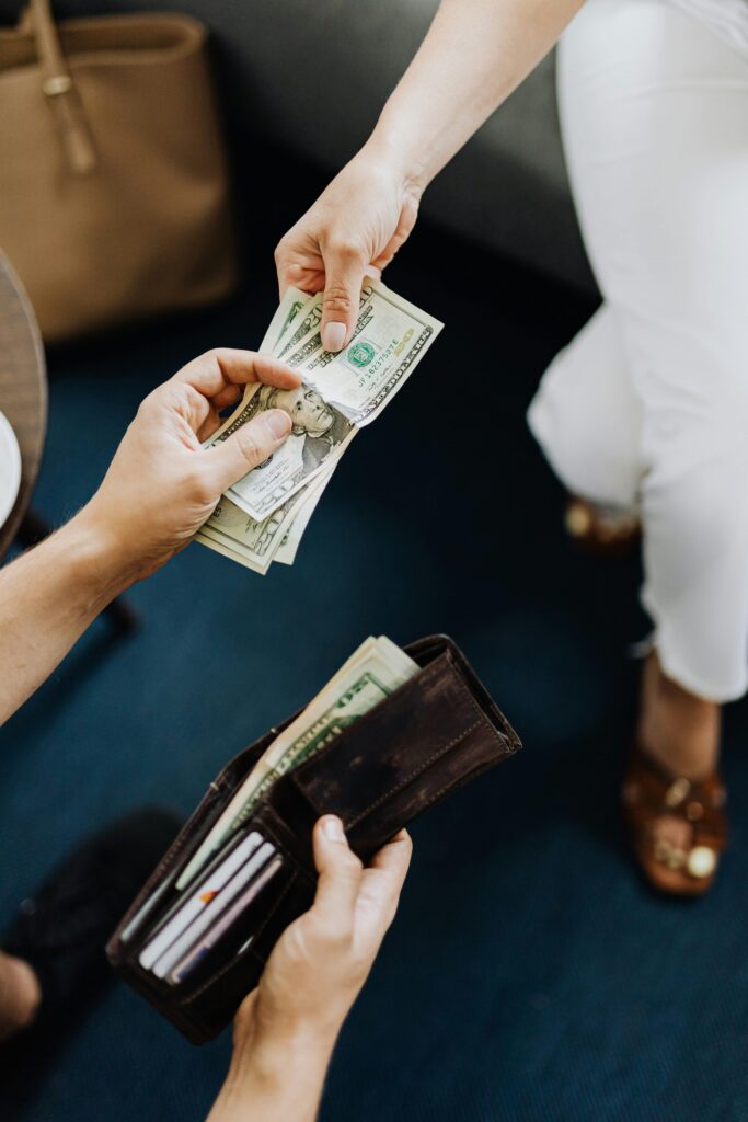 pexels-photo-4968385-4968385 Close-up of hands exchanging cash, representing a financial transaction or payment.