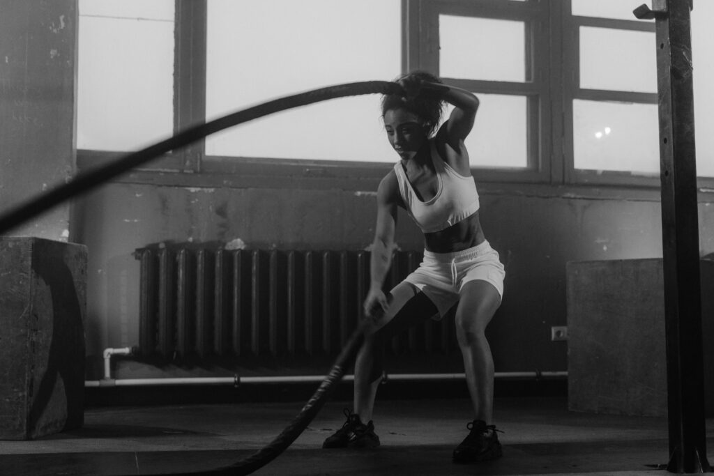 pexels-photo-6388387-6388387 Woman in a gym engaging in vigorous battle rope workout for fitness.