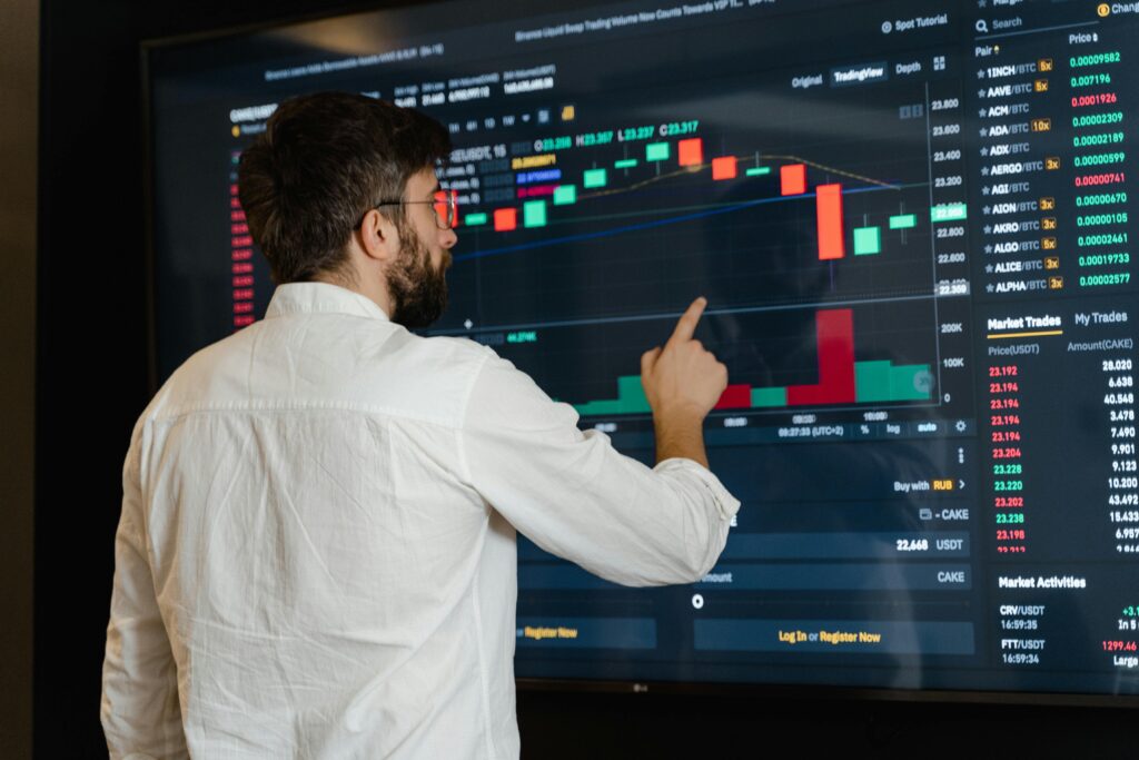 pexels-photo-7567554-7567554 A man analyzes cryptocurrency graphs on a touchscreen monitor in a modern office setting.
