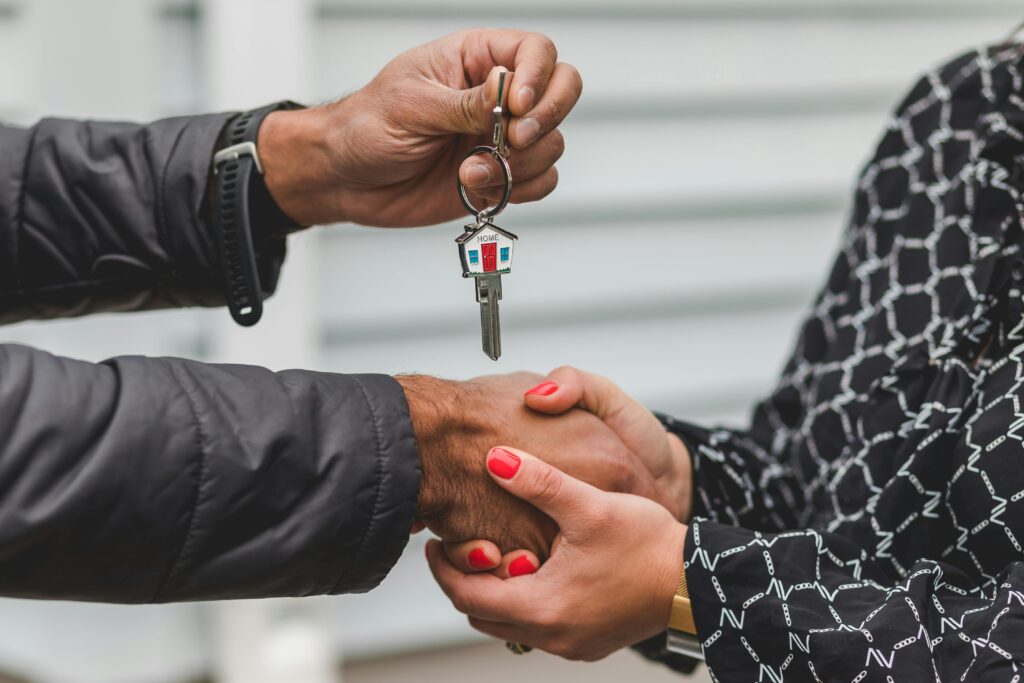 pexels-photo-8293778-8293778 Close-up of a realtor handing over a house key to a new homeowner, symbolizing ownership and investment.