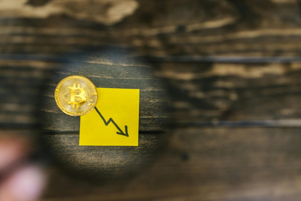 pexels-photo-8369839-8369839 A gold Bitcoin and downward trend arrow symbolizing cryptocurrency market decline.