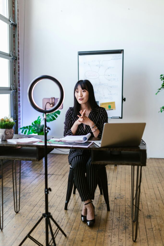 pexels-photo-8370761-8370761 A professional Asian woman using a laptop and ring light for an online meeting in a modern office.