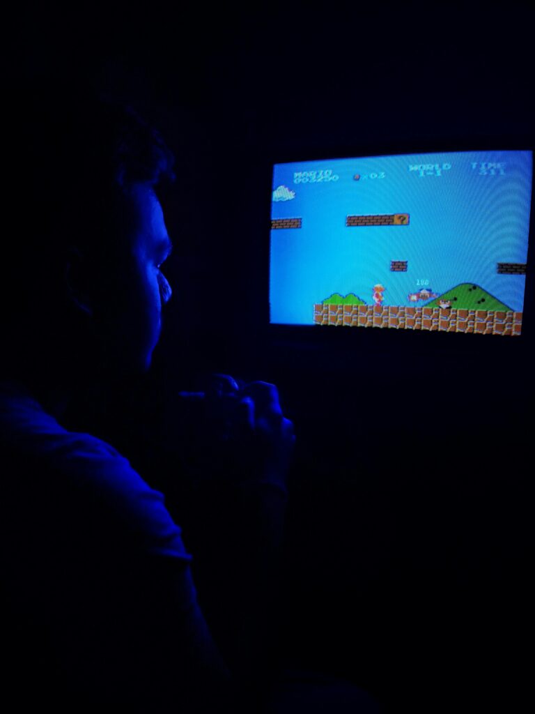 pexels-photo-2728255-2728255 Man playing Super Mario Bros on TV, capturing retro gaming nostalgia.