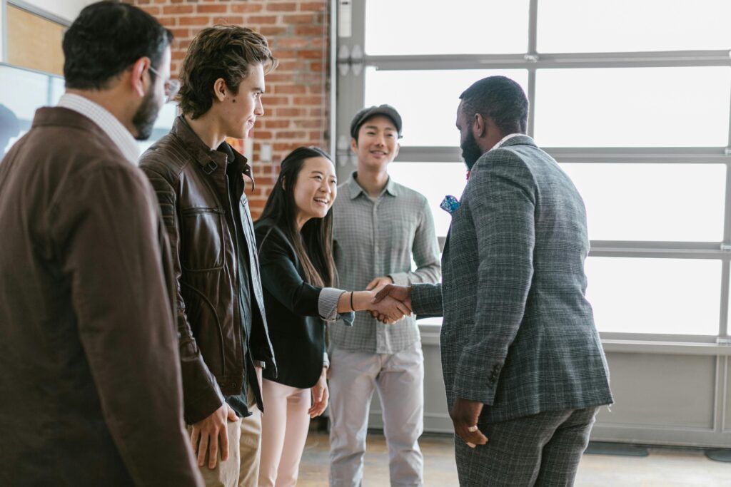 pexels-photo-7414275-7414275 A diverse group of business professionals engaging in a handshake and discussion in a modern office space.